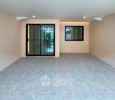 Spacious modern interior with large glass doors and tiled flooring, perfect for versatile living space.