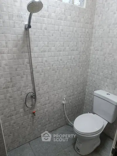 Modern bathroom with tiled walls and showerhead, featuring a sleek toilet design.