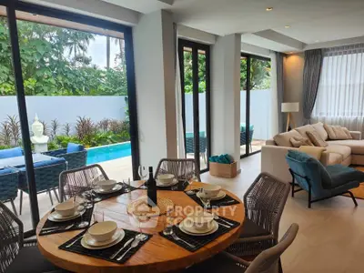 Luxurious open-plan living room with pool view, elegant dining setup, and modern decor.