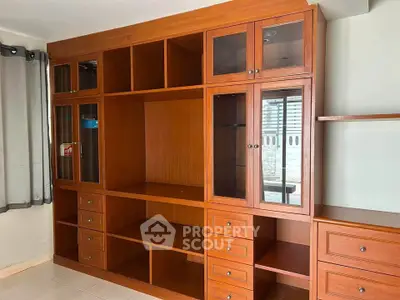 Spacious wooden storage unit in a well-lit room with tiled flooring and large windows.