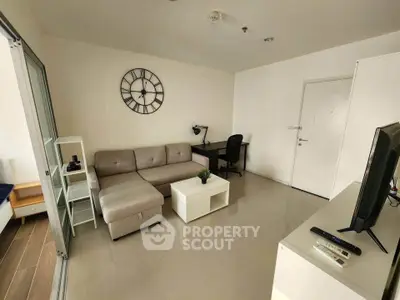 Modern living room with sectional sofa and wall clock, featuring a study desk and TV setup.