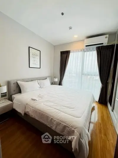 Spacious bedroom with modern decor and large window for natural light.