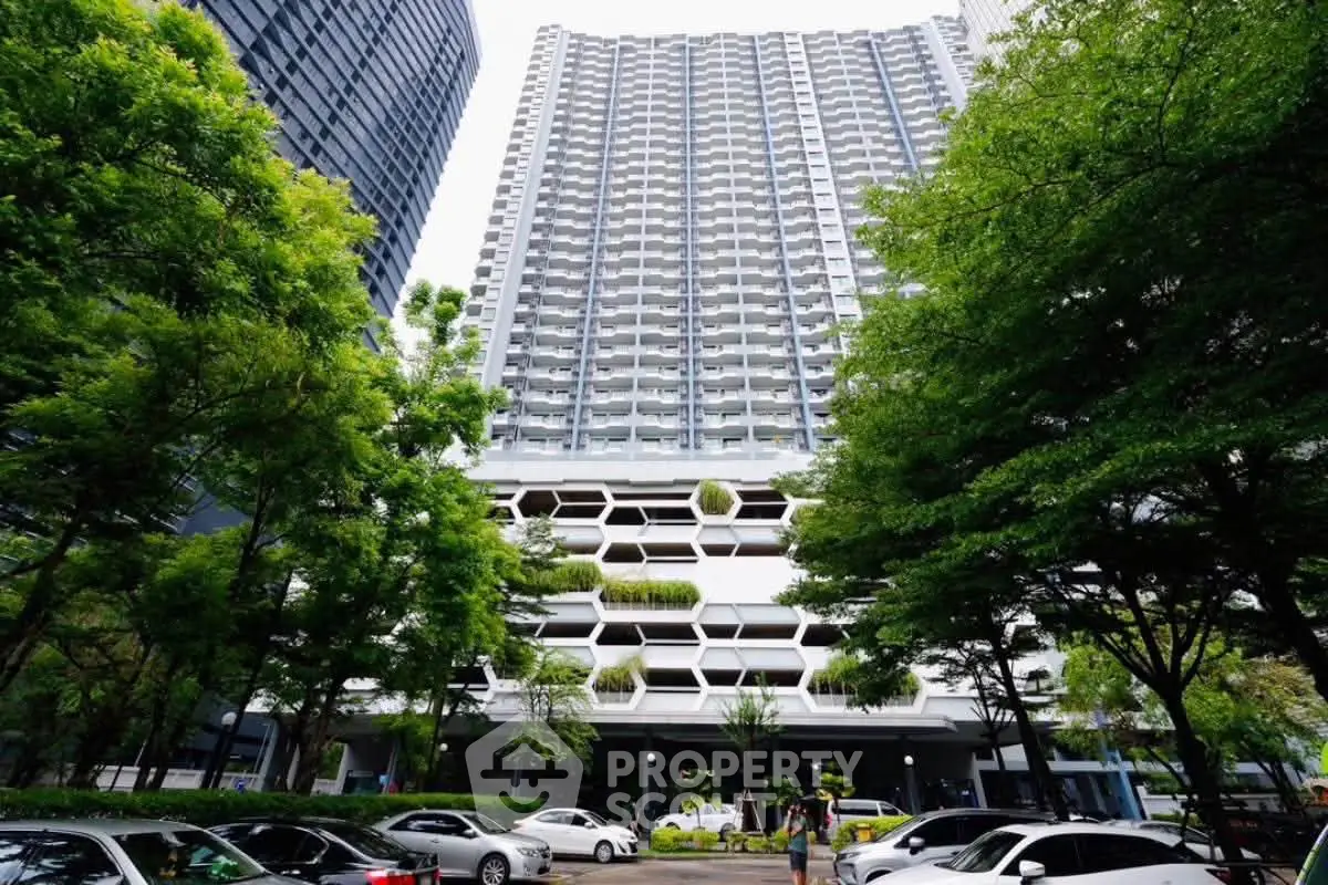 Modern high-rise building with unique facade and lush greenery in urban setting.