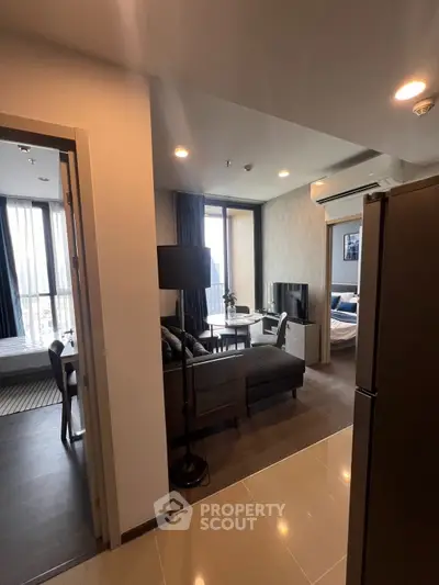 Modern open-layout apartment with living room and bedroom, featuring sleek furniture and large windows.