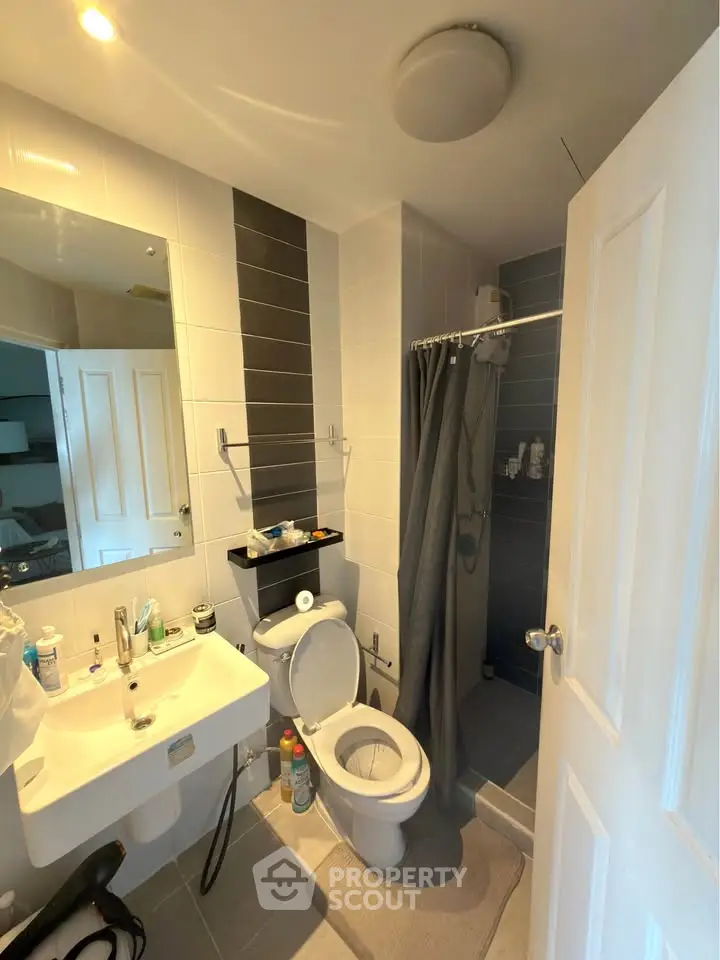 Modern bathroom with shower, toilet, and sink in a stylish apartment.