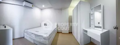 Modern minimalist bedroom with sleek white furniture and ample storage space.