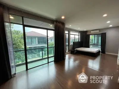 Spacious bedroom with gleaming hardwood floors, floor-to-ceiling windows offering a serene view, and ample natural light, perfect for a restful retreat.