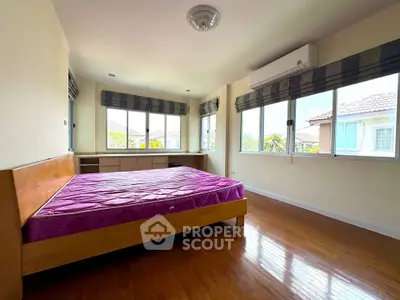 Spacious bedroom with large windows and wooden flooring in a modern home.