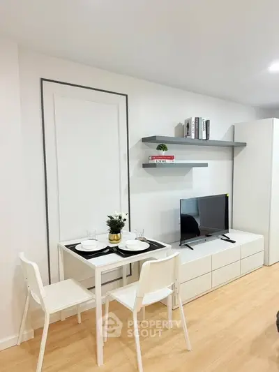 Modern living room with minimalist decor, featuring a small dining table and wall-mounted shelves.