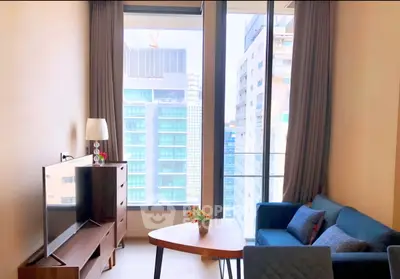 Modern living room with large windows offering city views, stylish furniture, and natural light.