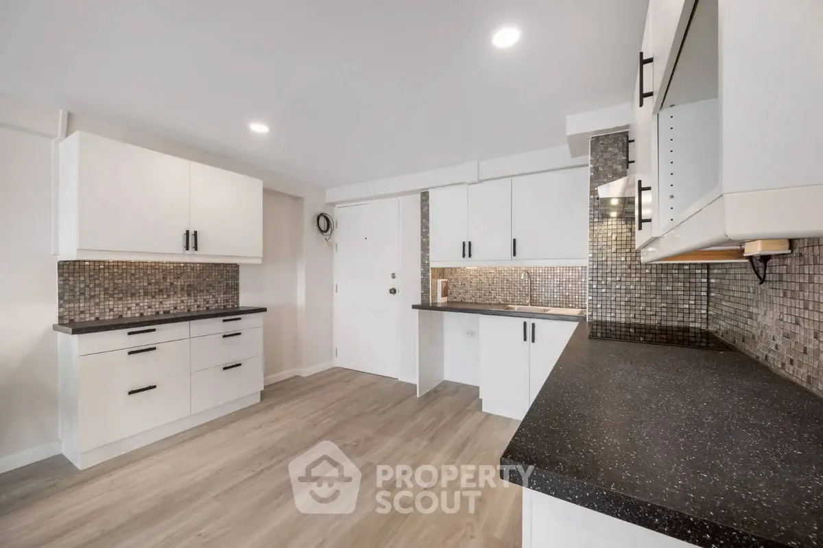 Modern kitchen with sleek white cabinets and stylish backsplash in a contemporary home.