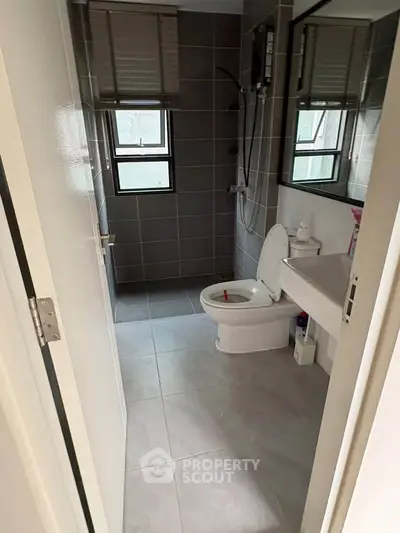 Modern bathroom with sleek design and natural light, featuring a toilet and shower area.
