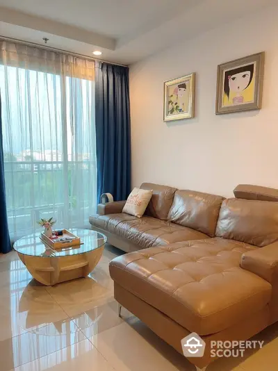 Cozy living room with leather sofa and modern decor, featuring large windows and natural light.