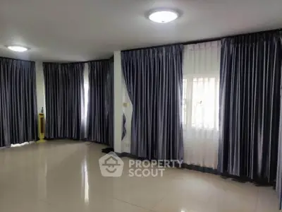 Spacious living room with elegant curtains and polished flooring, perfect for modern living.