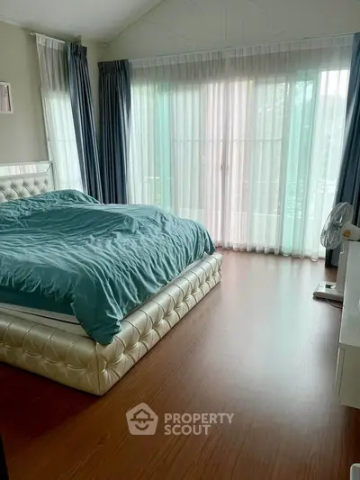 Spacious bedroom with elegant bed and large windows offering natural light.