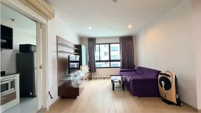 Modern living room with purple sofa and sleek entertainment unit in a bright apartment.