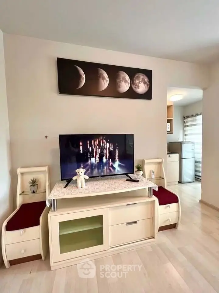 Cozy living room with modern decor and TV, adjacent to a compact kitchen area.
