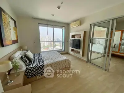 Spacious bedroom with city view, modern decor, and sliding glass doors in a high-rise apartment.