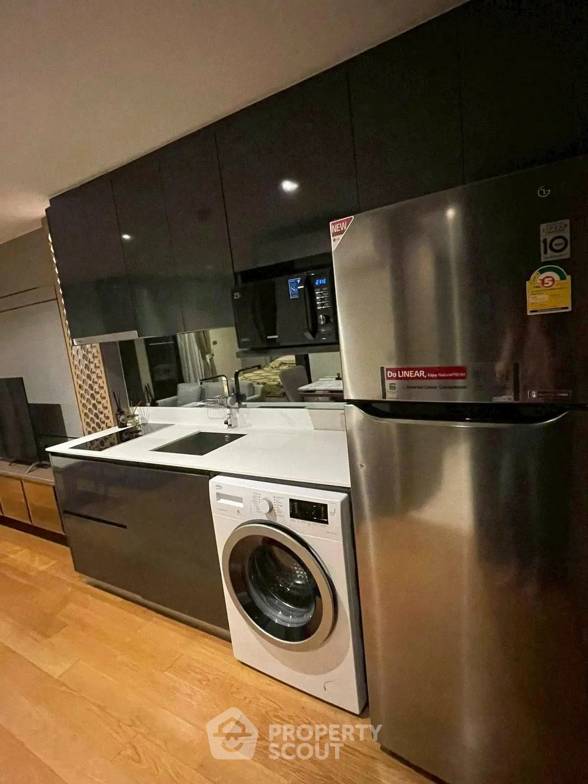 Modern kitchen with sleek cabinets, washing machine, and stainless steel fridge in a stylish apartment.