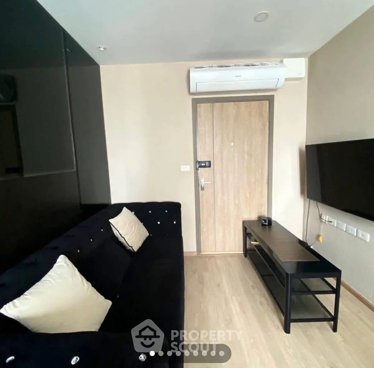 Modern living room with sleek black sofa and wall-mounted TV