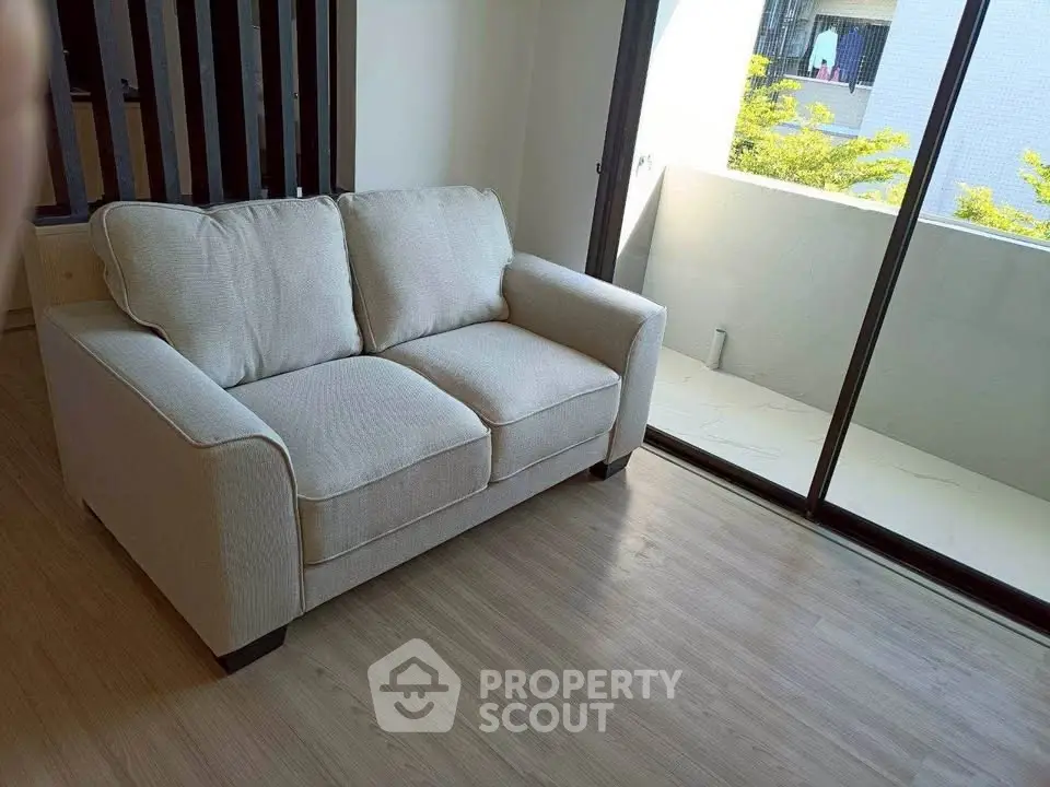 Cozy living room with a plush sofa and balcony view, perfect for relaxation.