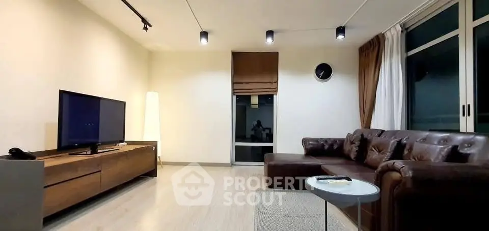 Modern living room with leather sofa and sleek TV setup in a stylish apartment.