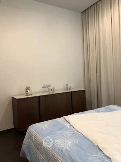 Cozy bedroom with elegant decor and soft lighting, featuring a stylish cabinet and luxurious bedding.