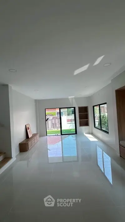 Spacious modern living room with large windows and glossy tiled floor, offering a bright and airy ambiance.
