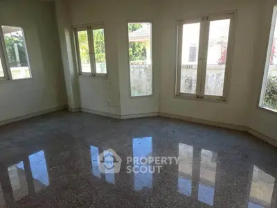 Spacious empty room with large windows and glossy tiled floor, offering abundant natural light and garden views.