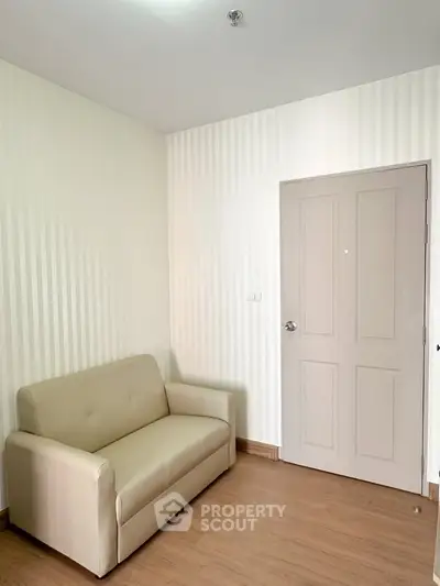 Cozy living room with beige sofa and wooden flooring, perfect for relaxation.
