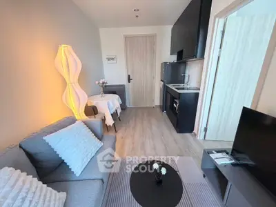 Modern living room with cozy seating and compact kitchen in stylish apartment.