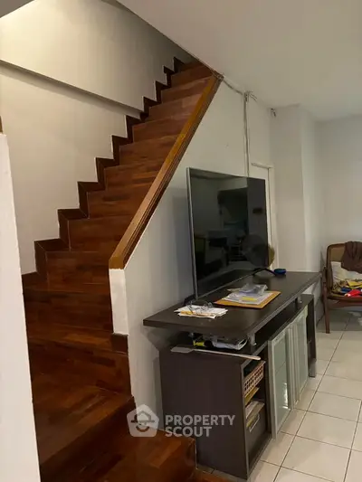 Modern living room with wooden staircase and sleek TV setup