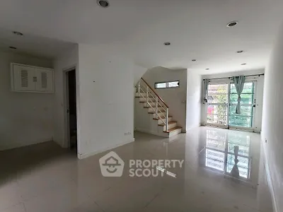 Spacious modern living room with glossy tiled floors and staircase
