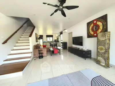 Spacious modern living room with stylish decor and open layout, featuring a staircase and ceiling fan.