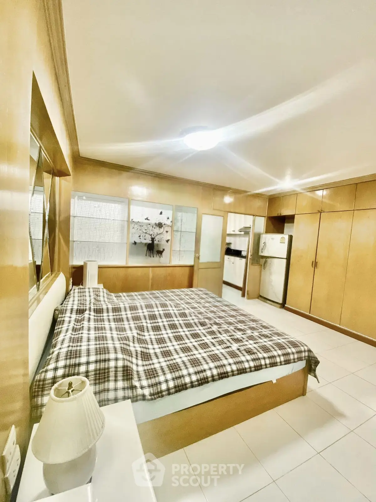 Spacious bedroom with cozy plaid bedding and ample storage in a modern apartment.