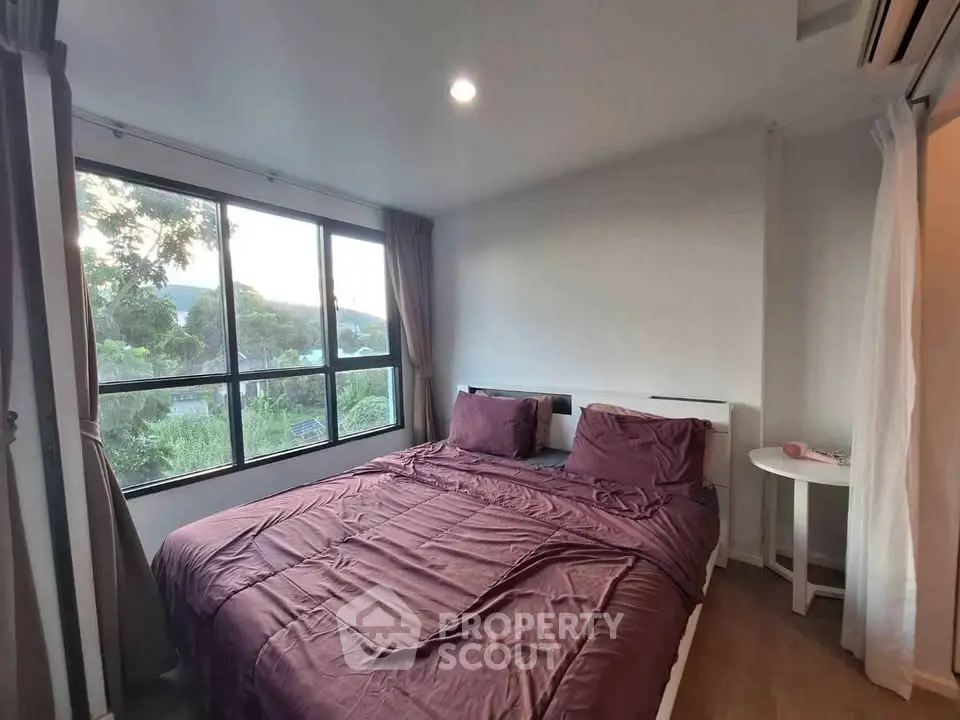 Cozy bedroom with large windows offering scenic views and elegant decor.