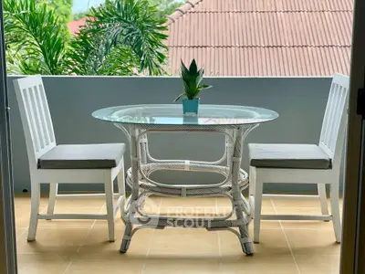 Charming balcony with stylish outdoor furniture and lush greenery view, perfect for relaxation.