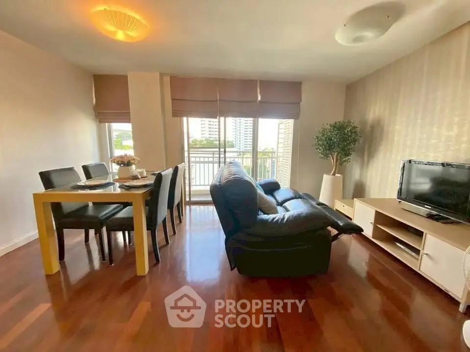 Spacious living room with modern furniture and city view balcony in a high-rise apartment.