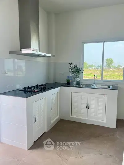 Modern kitchen with sleek gas stove and ample natural light, perfect for culinary enthusiasts.