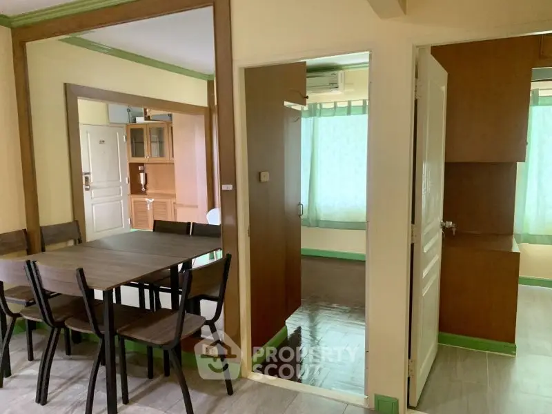 Spacious dining area with wooden furniture and green accents in a cozy apartment.