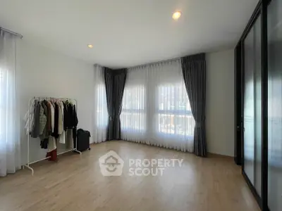 Spacious and well-lit empty room with large windows draped in elegant curtains, ideal for a personalized living space.