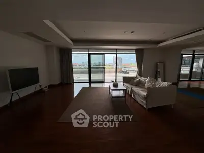 Spacious living room with modern decor and large windows offering city views.