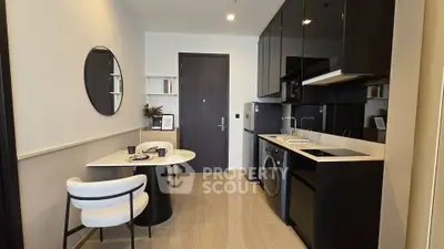 Modern kitchen with sleek black cabinets and integrated appliances in a stylish apartment.