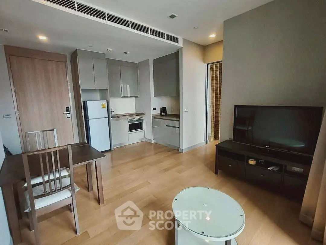 Modern living room with open kitchen, sleek furniture, and wooden flooring in a stylish apartment.