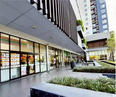 Modern apartment building exterior with landscaped garden and seating area.