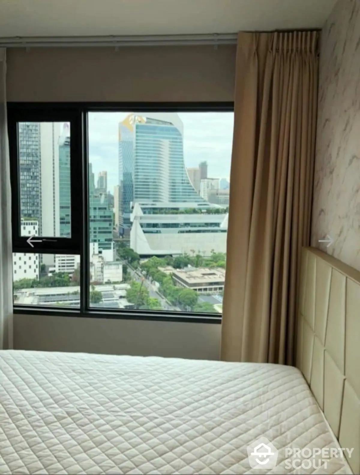 Modern bedroom with city view from large window in high-rise apartment