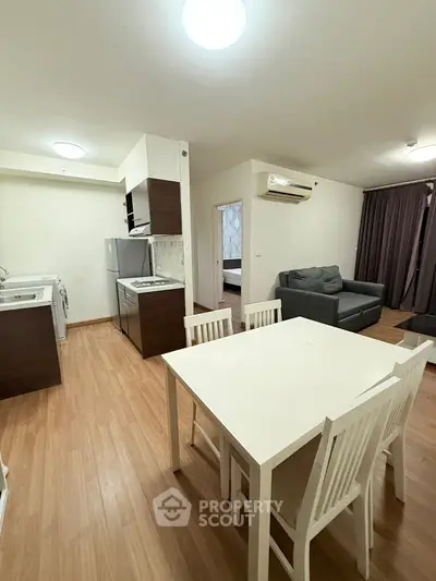 Modern open-plan living room with kitchen and dining area, featuring wooden flooring and contemporary furniture.