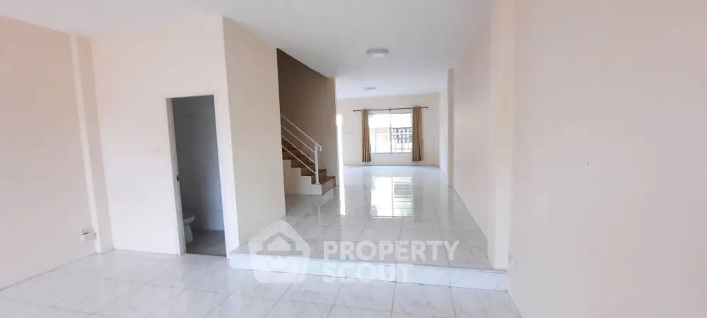 Spacious open-plan living area with sleek tiled flooring and staircase.