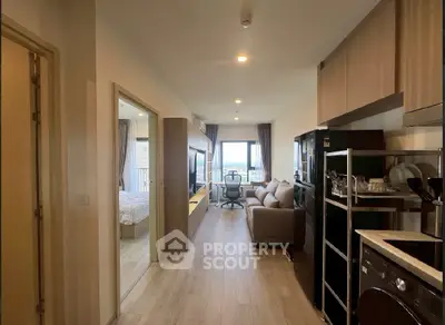 Modern apartment interior with open layout, featuring a cozy living room and kitchen area, leading to a bedroom with a view.