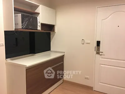 Compact kitchen area with modern cabinetry and microwave, ideal for small apartments.
